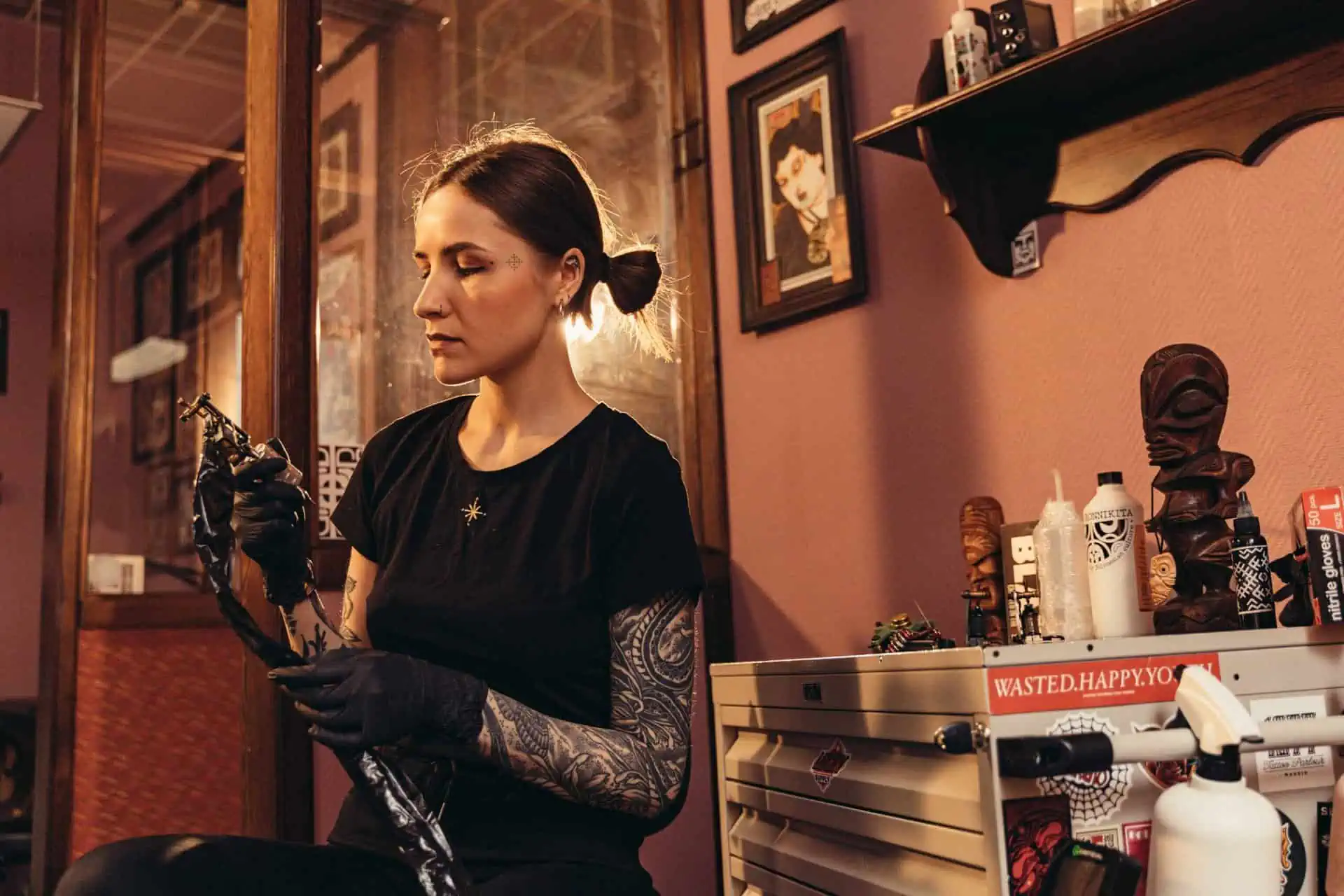 female tattoo artist holding a tattoo machine and checking it over.